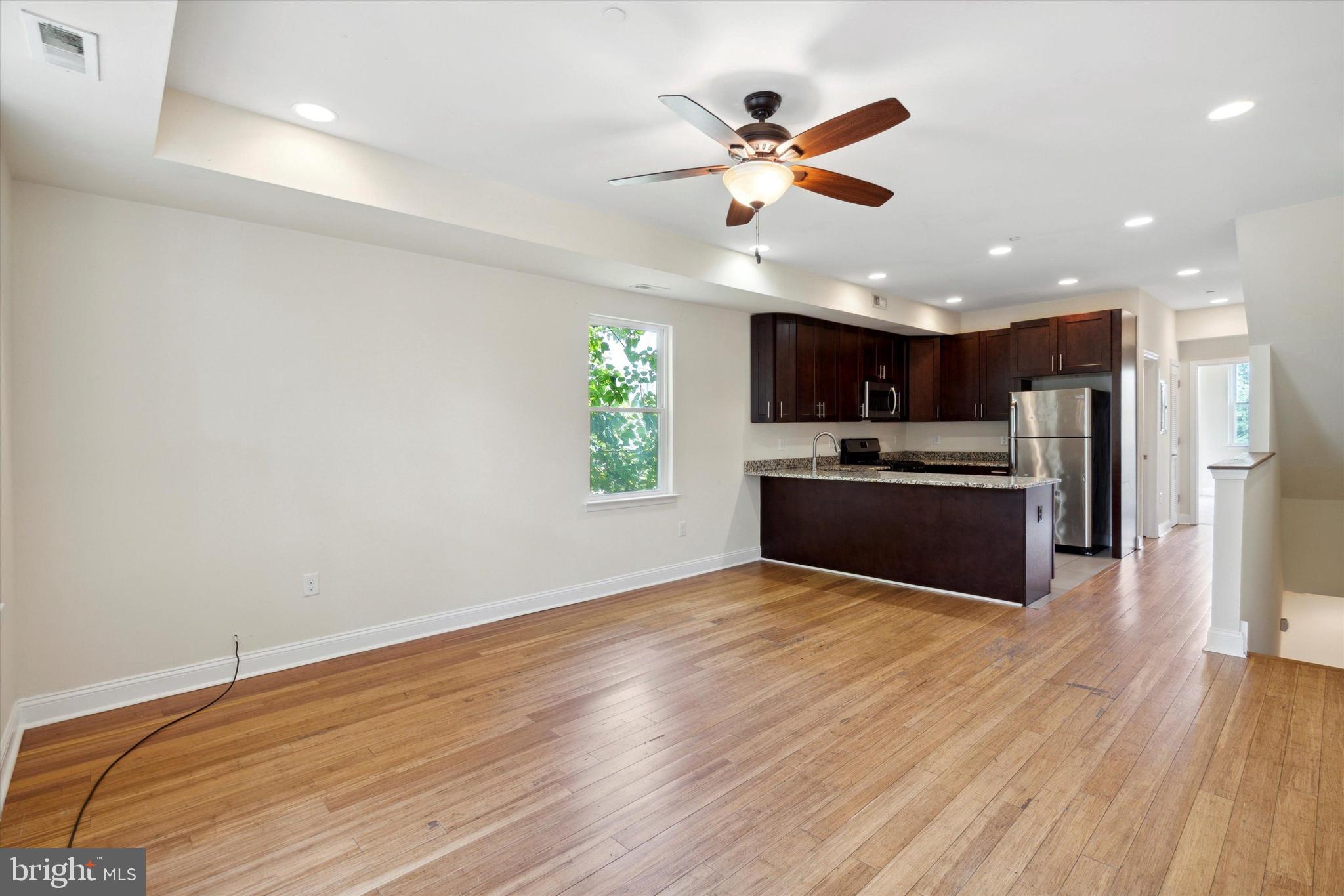 a view of kitchen with kitchen island wooden floor center island and stainless steel appliances