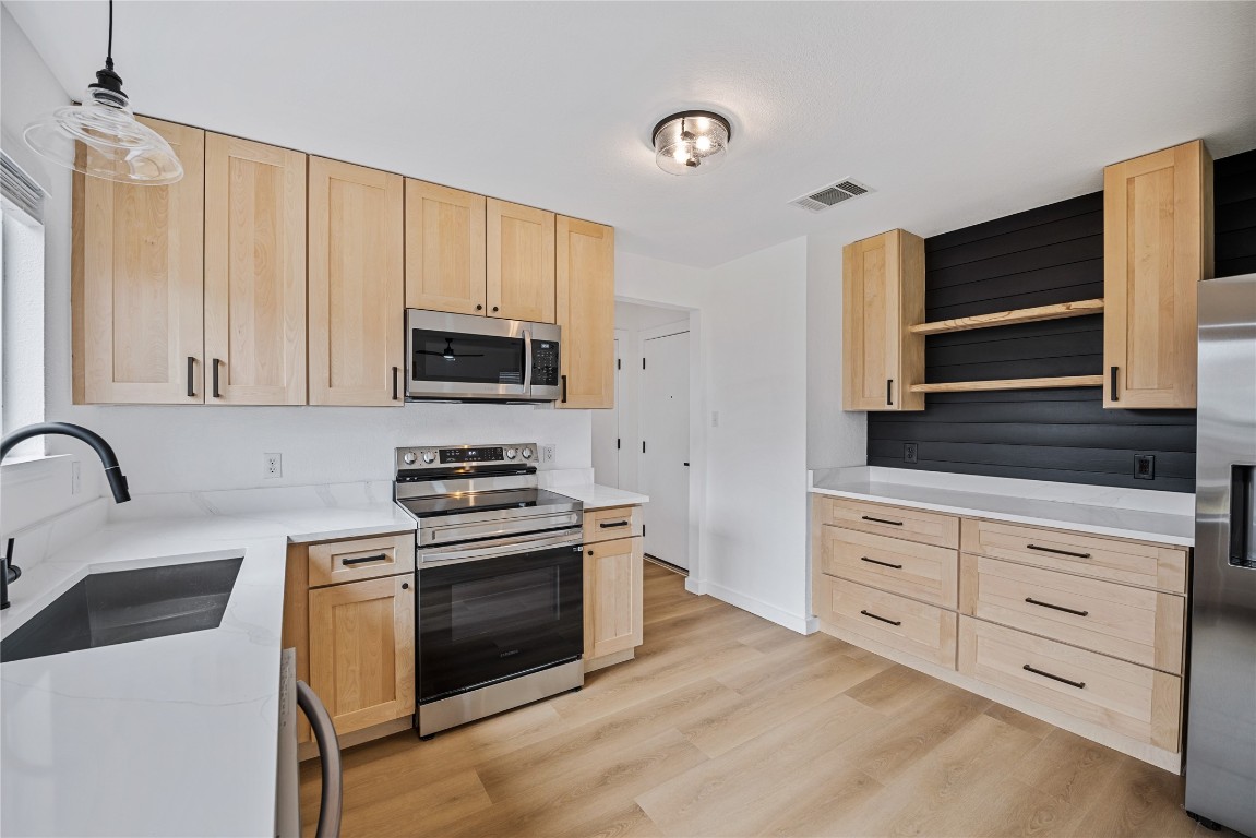 a kitchen with granite countertop white cabinets and stainless steel appliances