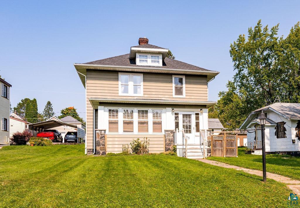 View of front of property featuring a front yard and a carport