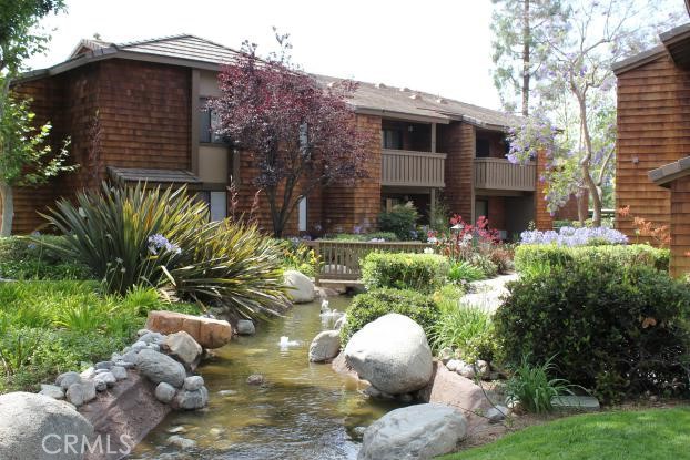 a backyard of a house with table and chairs plants and large tree