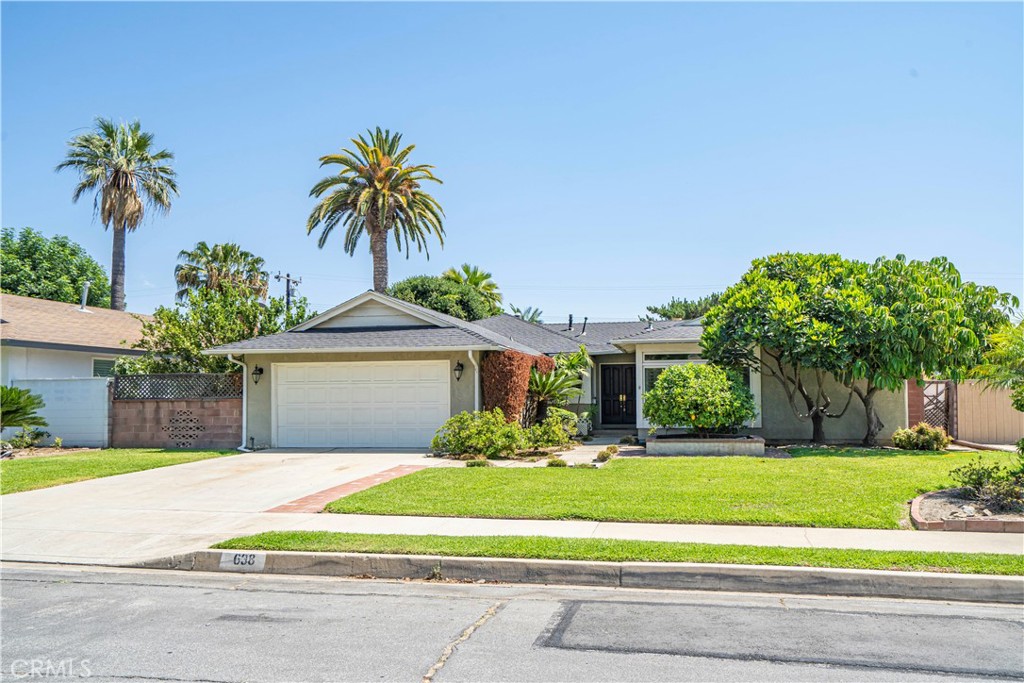 a front view of a house with a garden and palm trees