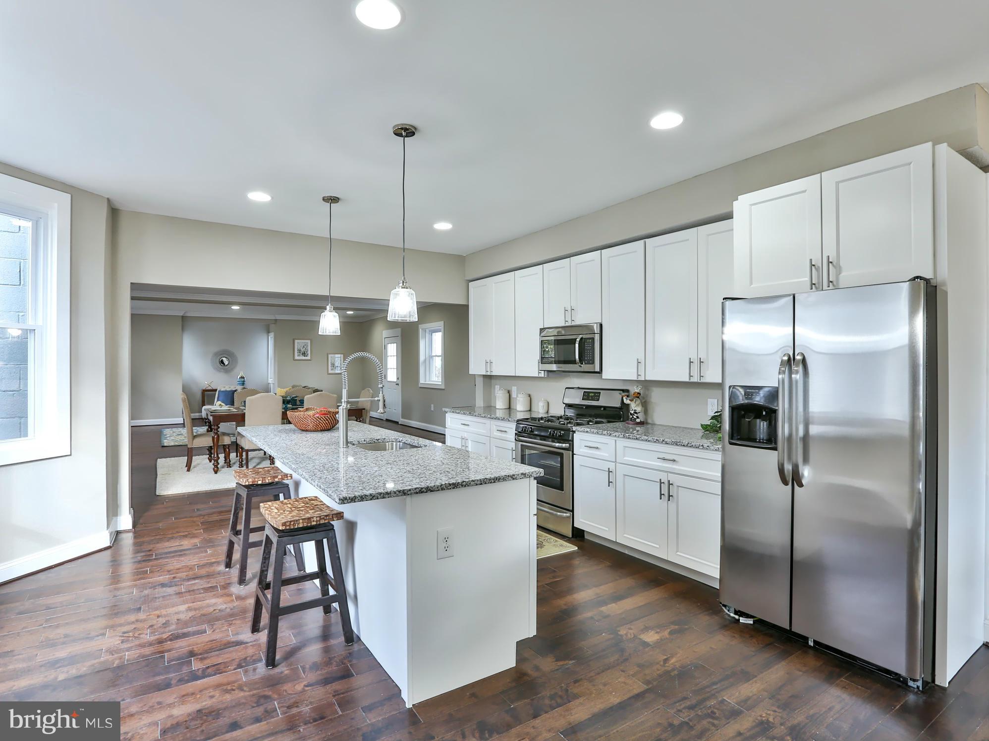 a kitchen with stainless steel appliances granite countertop a table chairs refrigerator and microwave