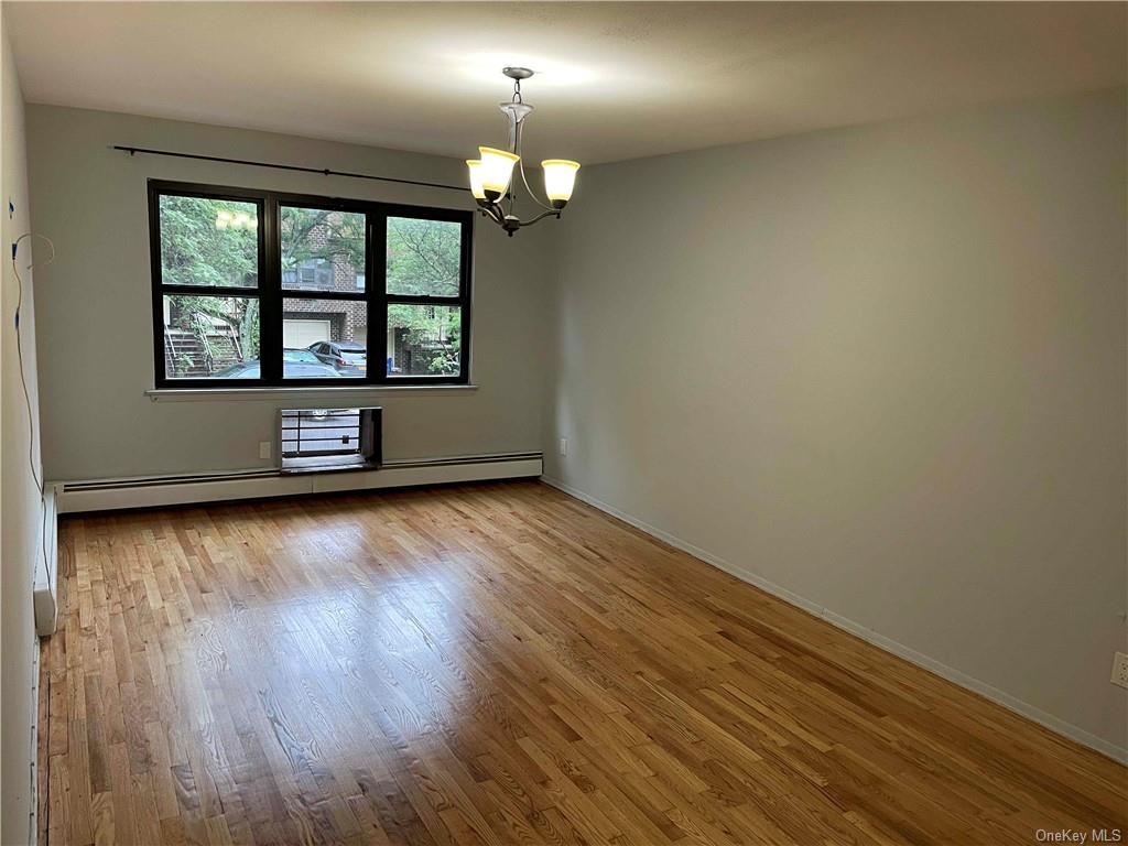 Spare room featuring baseboard heating, light hardwood / wood-style flooring, and a notable chandelier