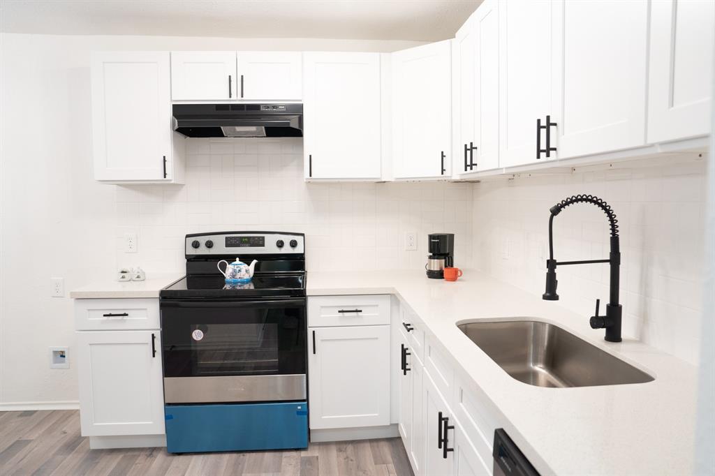 a kitchen with stainless steel appliances kitchen island a stove a sink and white cabinets