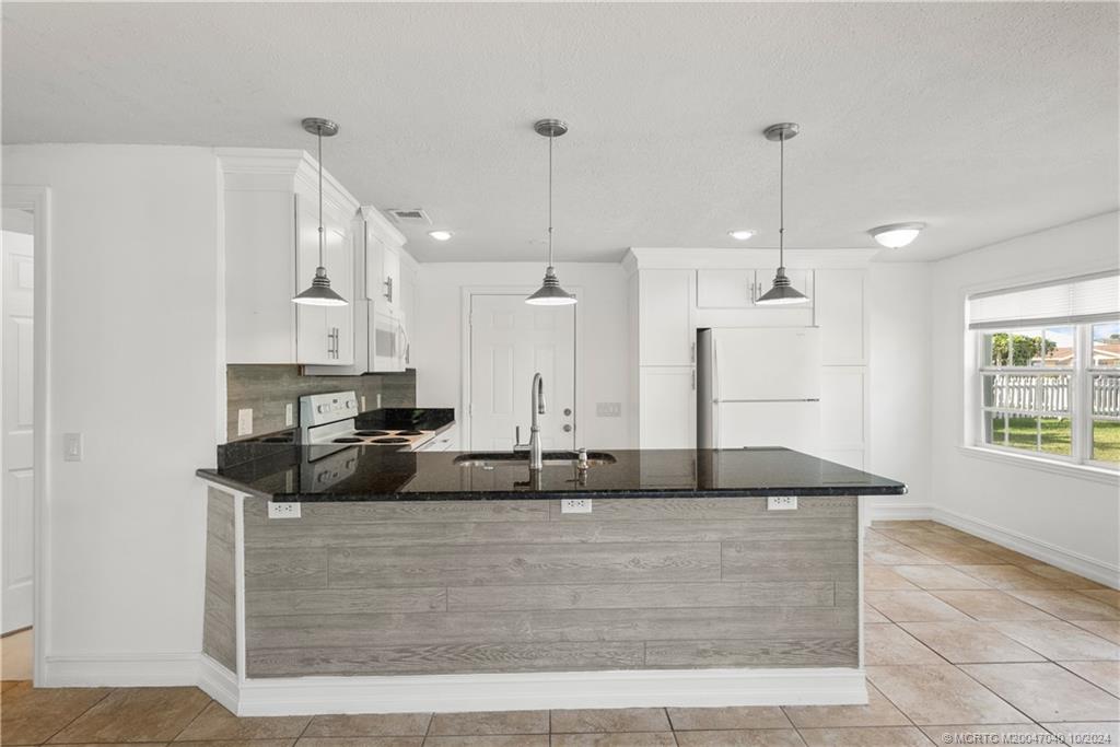 a kitchen with kitchen island stainless steel appliances granite countertop a sink a counter top space and cabinets