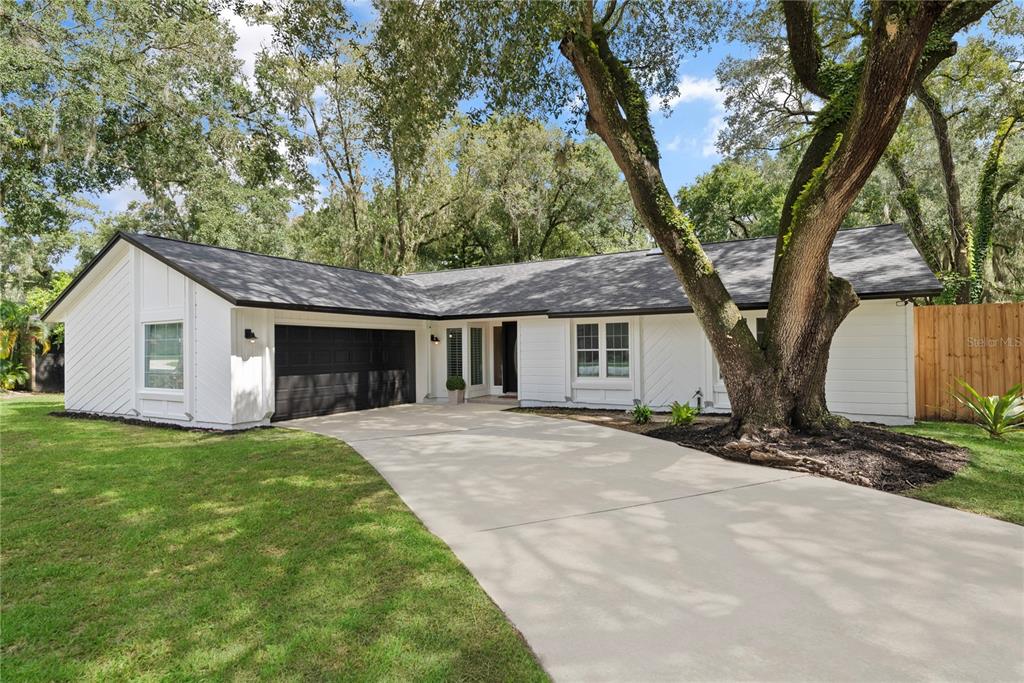 a front view of a house with a garden and trees