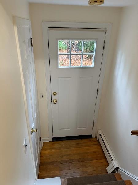 Doorway to outside featuring a baseboard radiator and dark wood-type flooring