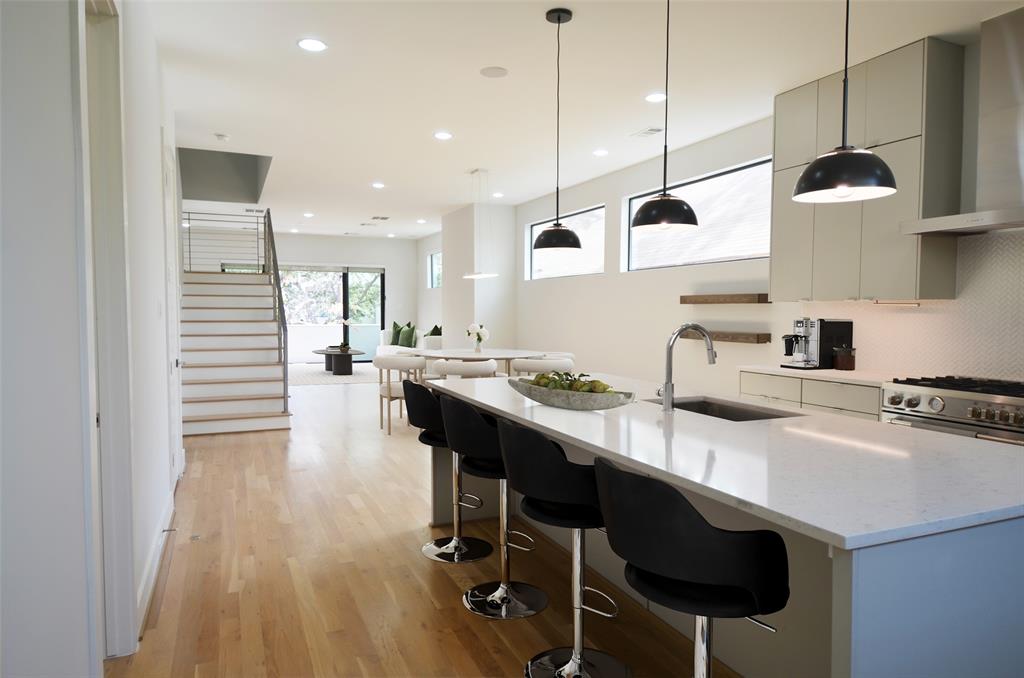 a kitchen with stainless steel appliances granite countertop a sink a stove and chairs with wooden floor