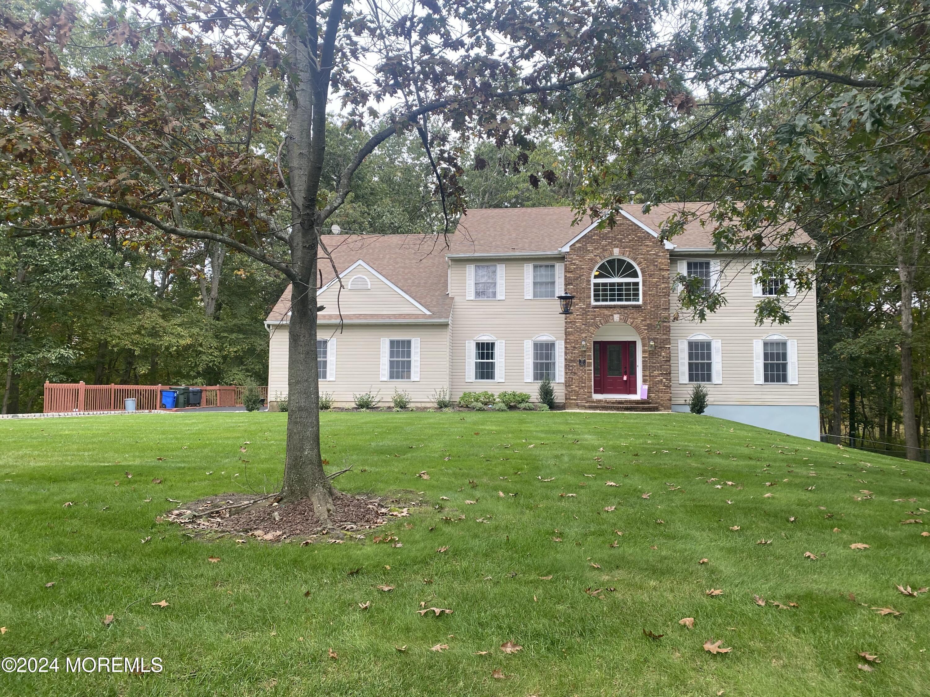 a view of a yard in front of a house with plants and large tree