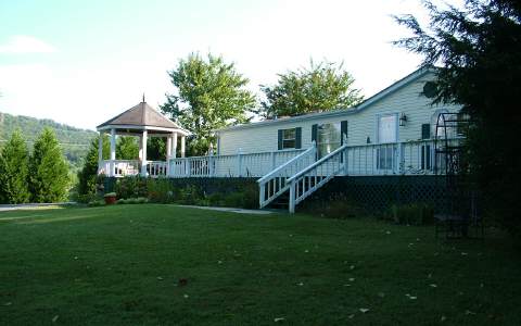 a view of a house with a yard and large trees