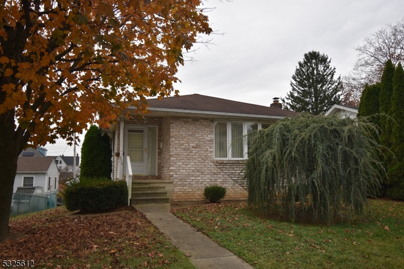 a view of a brick house with a small yard and a large tree