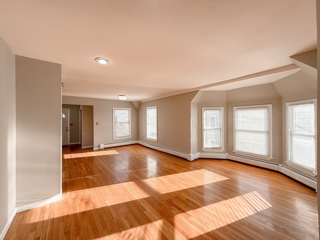 a view of an empty room with window and wooden floor