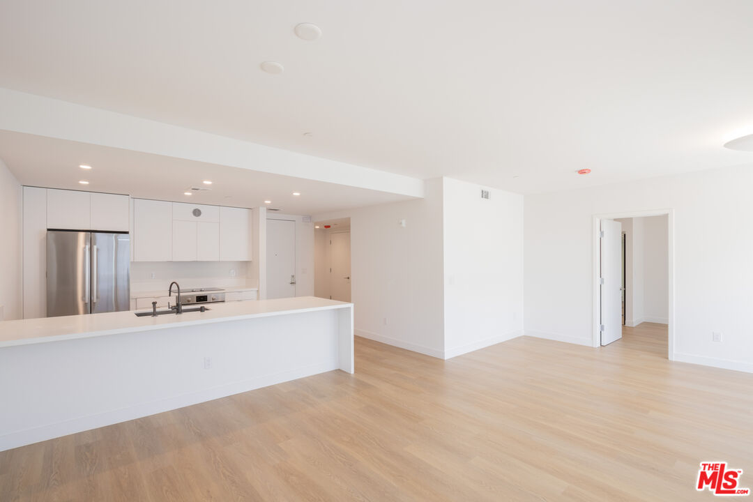 a large white kitchen with kitchen island a sink a stove and a refrigerator