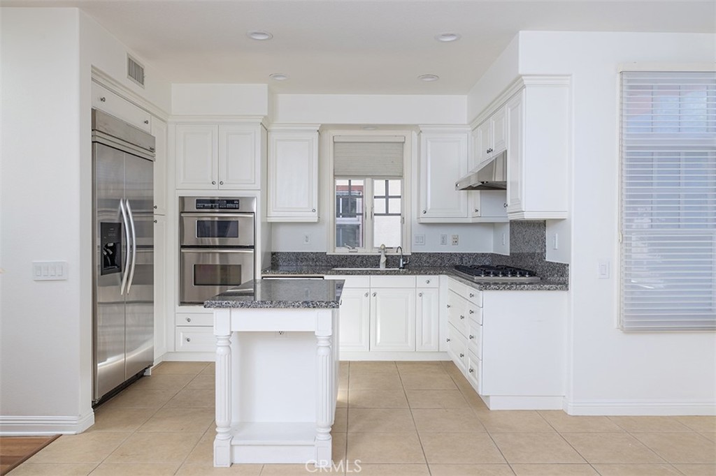 a kitchen with stainless steel appliances a stove a sink and white cabinets