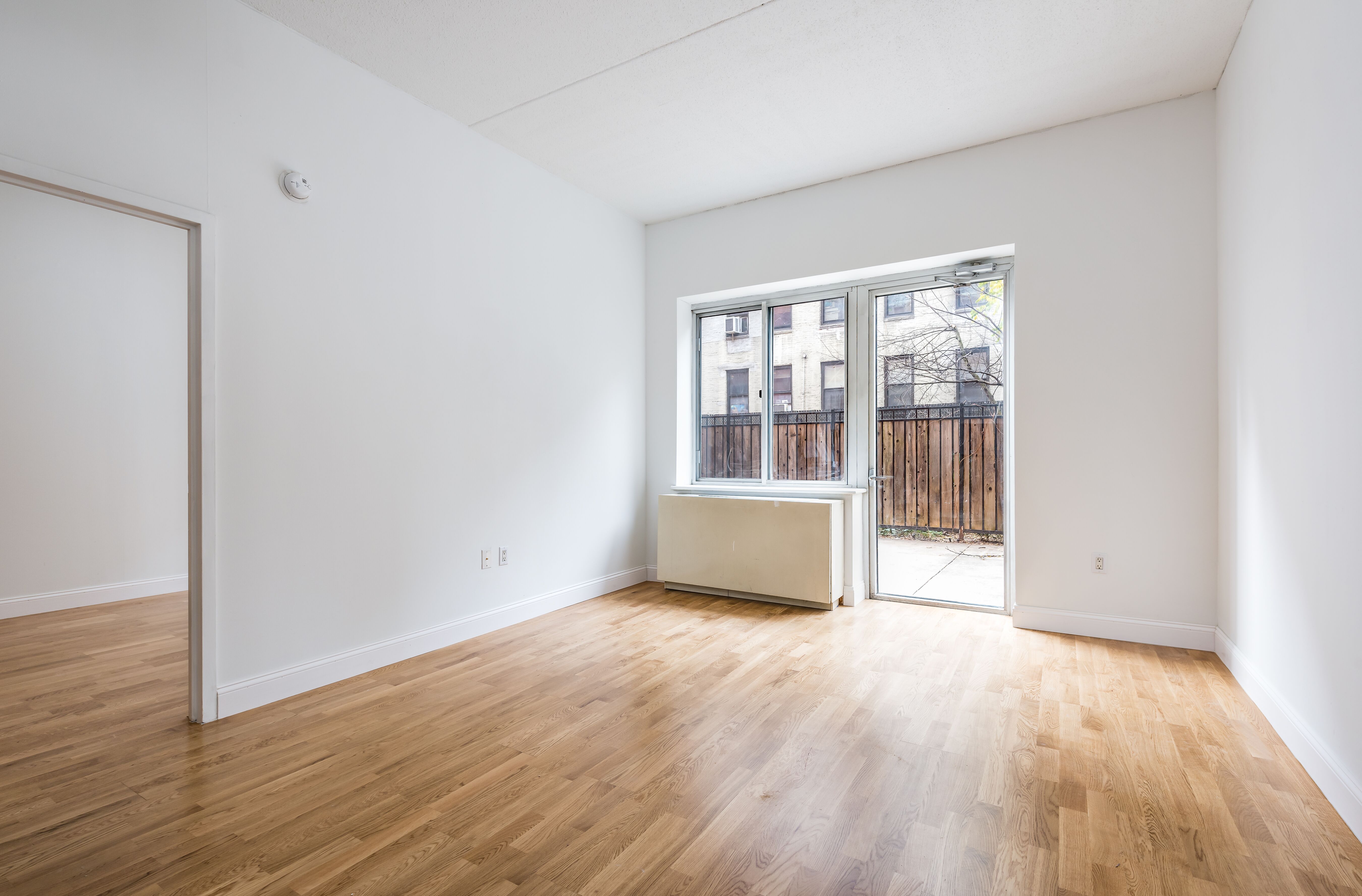 a view of an empty room with wooden floor and a window