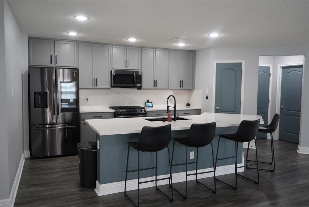 a kitchen with refrigerator a sink and chairs