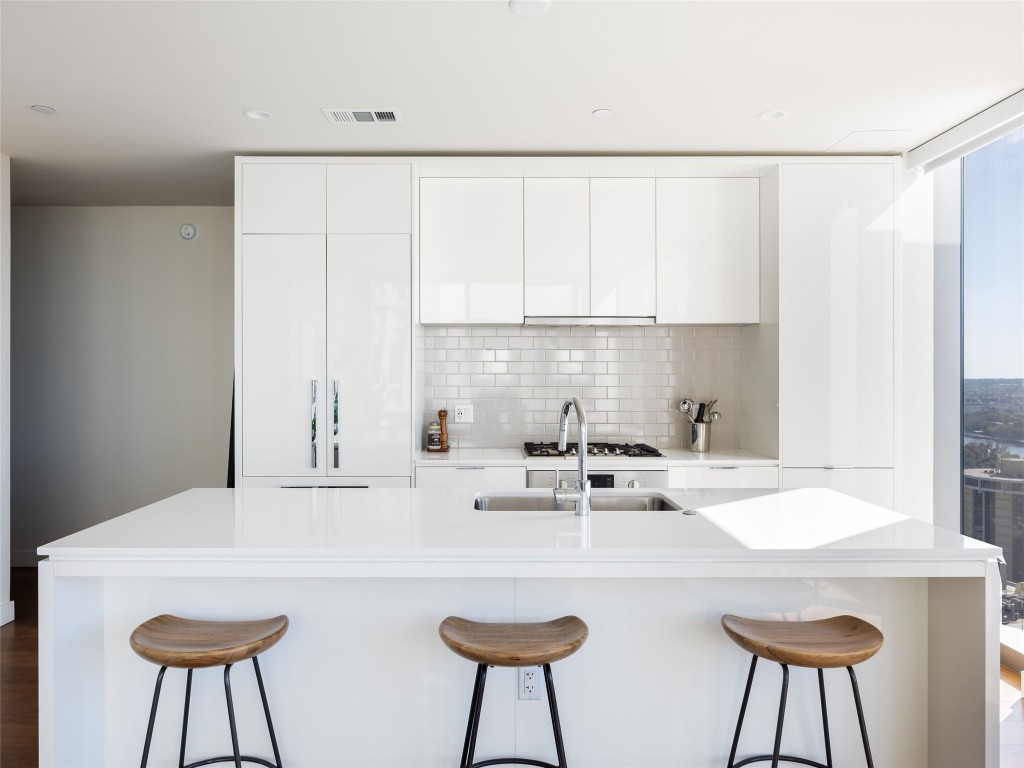 a kitchen with stainless steel appliances a white table chairs and a refrigerator