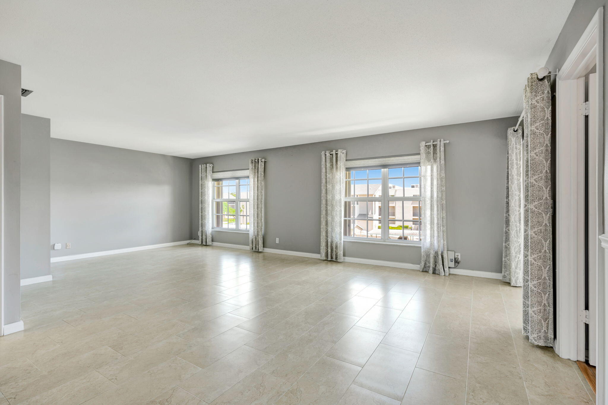 a view of an empty room with window and wooden floor