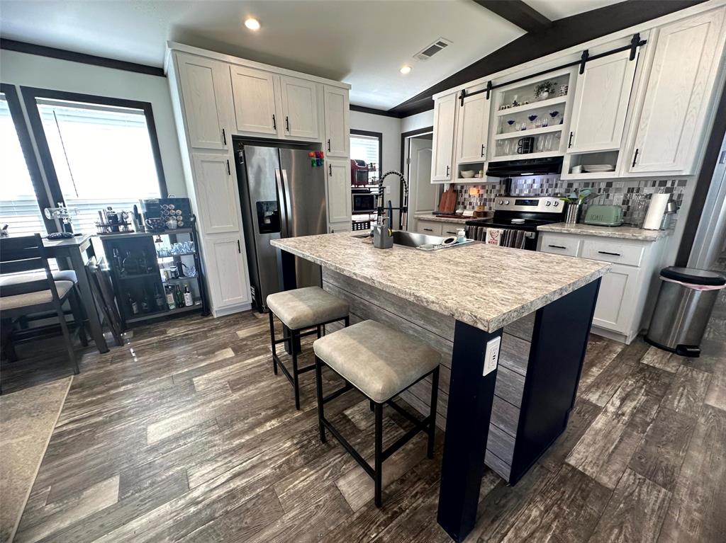 a large kitchen with stainless steel appliances granite countertop a table chairs and a refrigerator