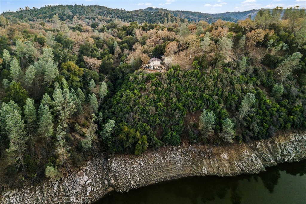 an aerial view of residential house with outdoor space and trees all around