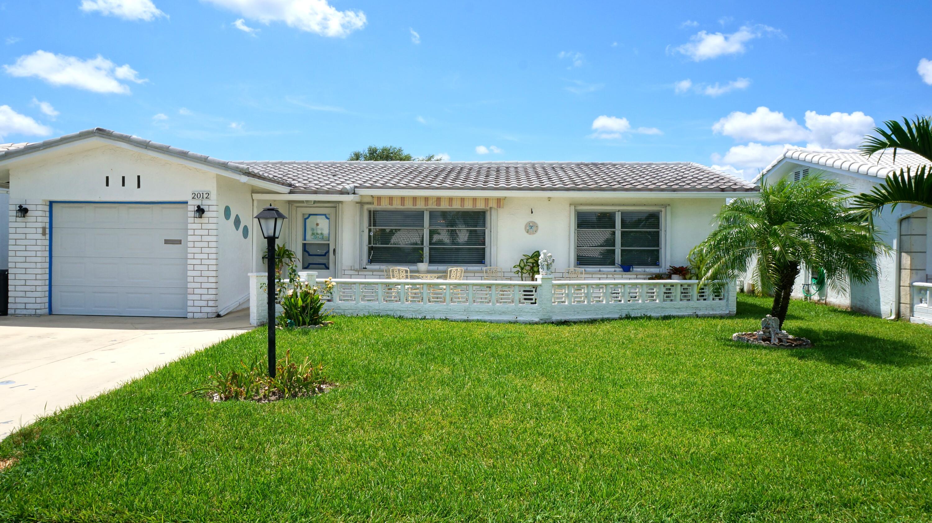 a front view of house with yard and glass top table and chairs