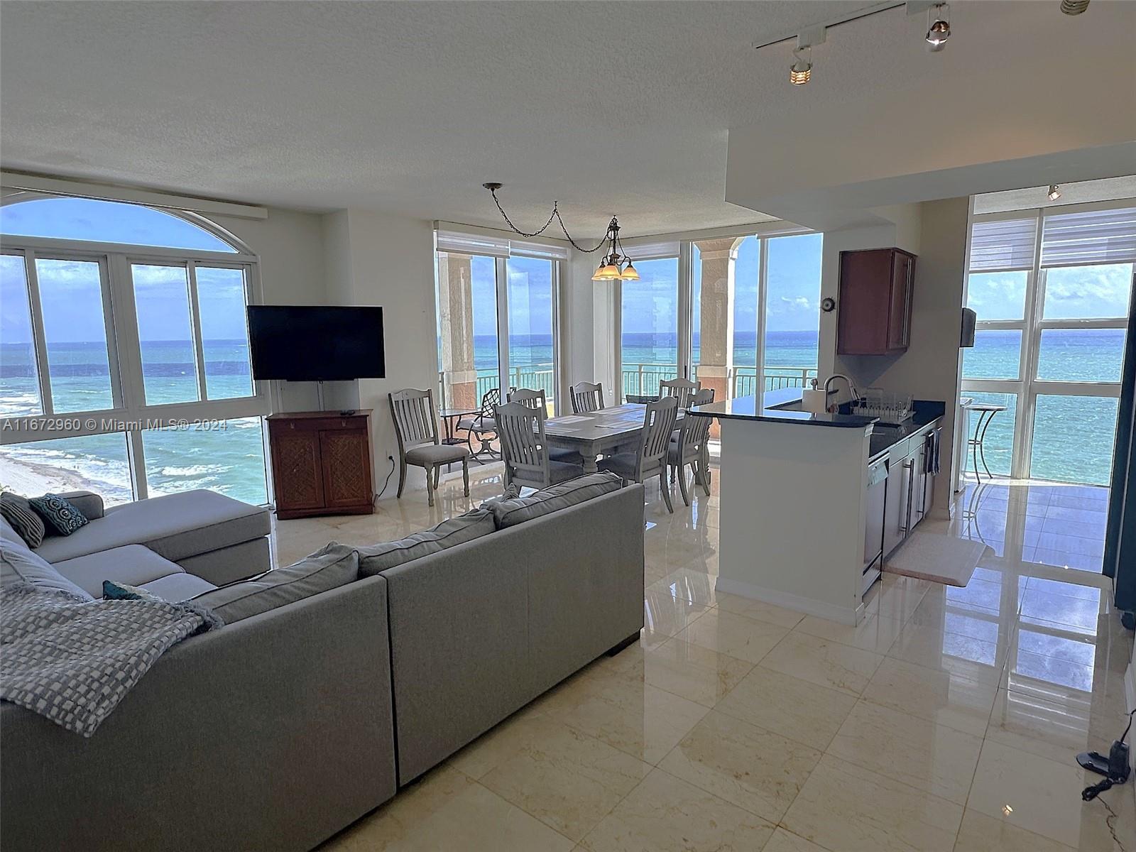 a living room with furniture a flat screen tv and large windows