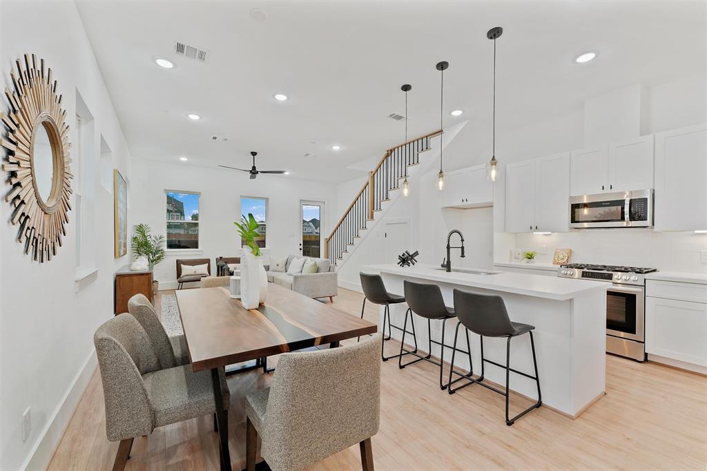 a view of kitchen with kitchen island stainless steel appliances refrigerator stove dining table and chairs