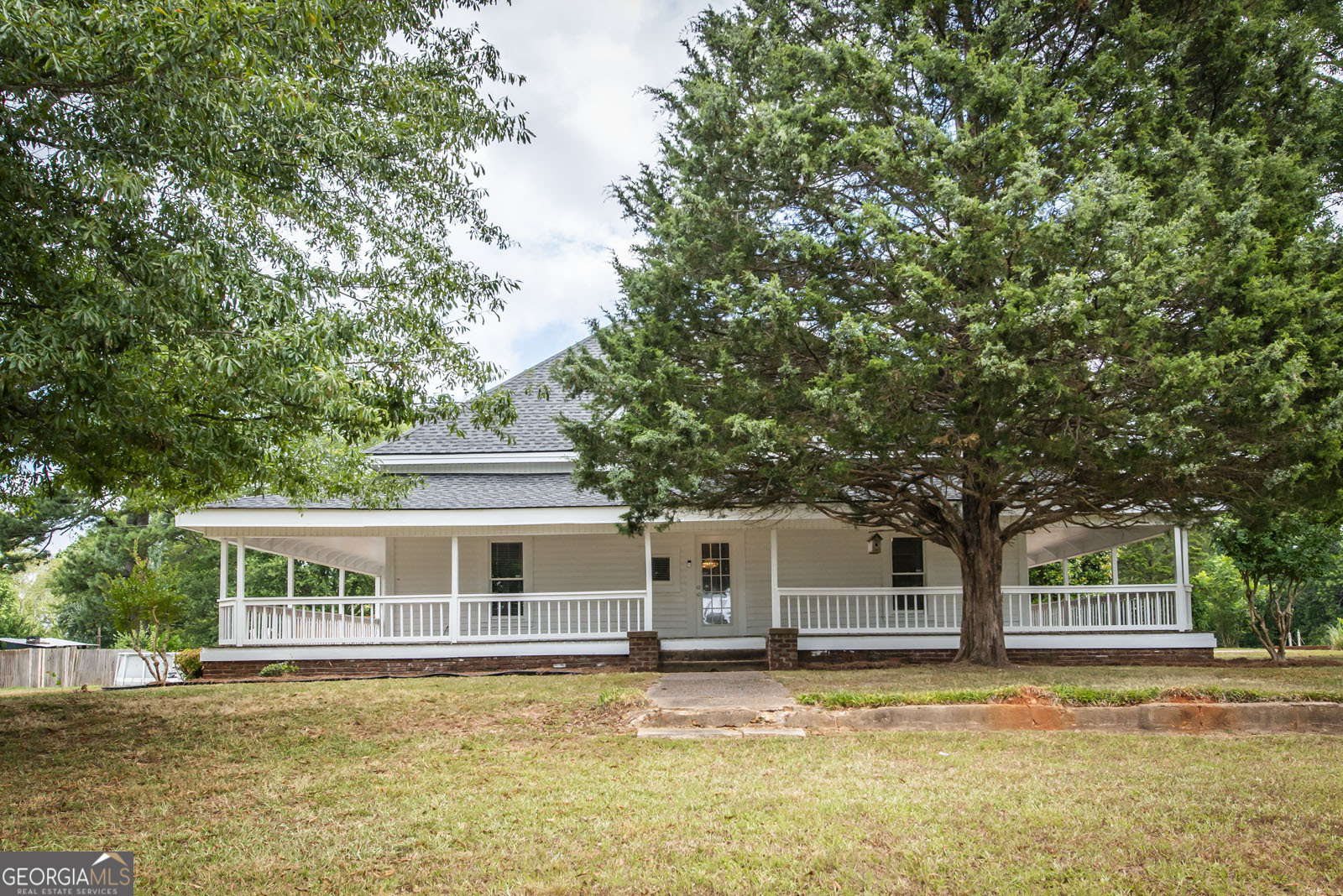 a front view of a house with a garden and trees