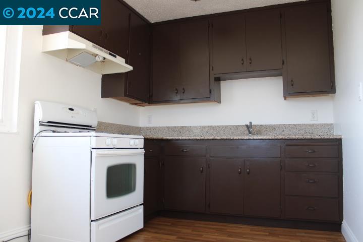 a kitchen with a sink and a stove with wooden floor