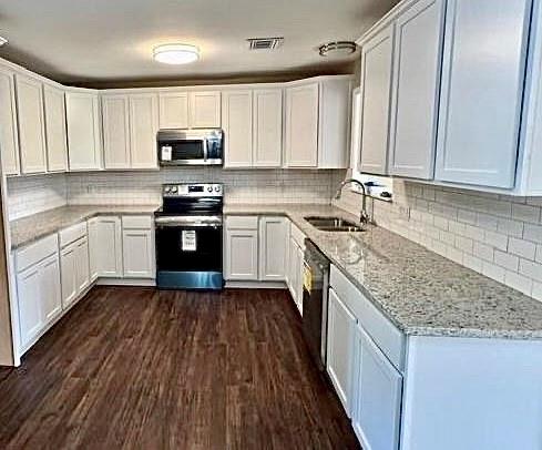 a kitchen with stainless steel appliances granite countertop wooden cabinets a sink and dishwasher a stove top oven with wooden floor