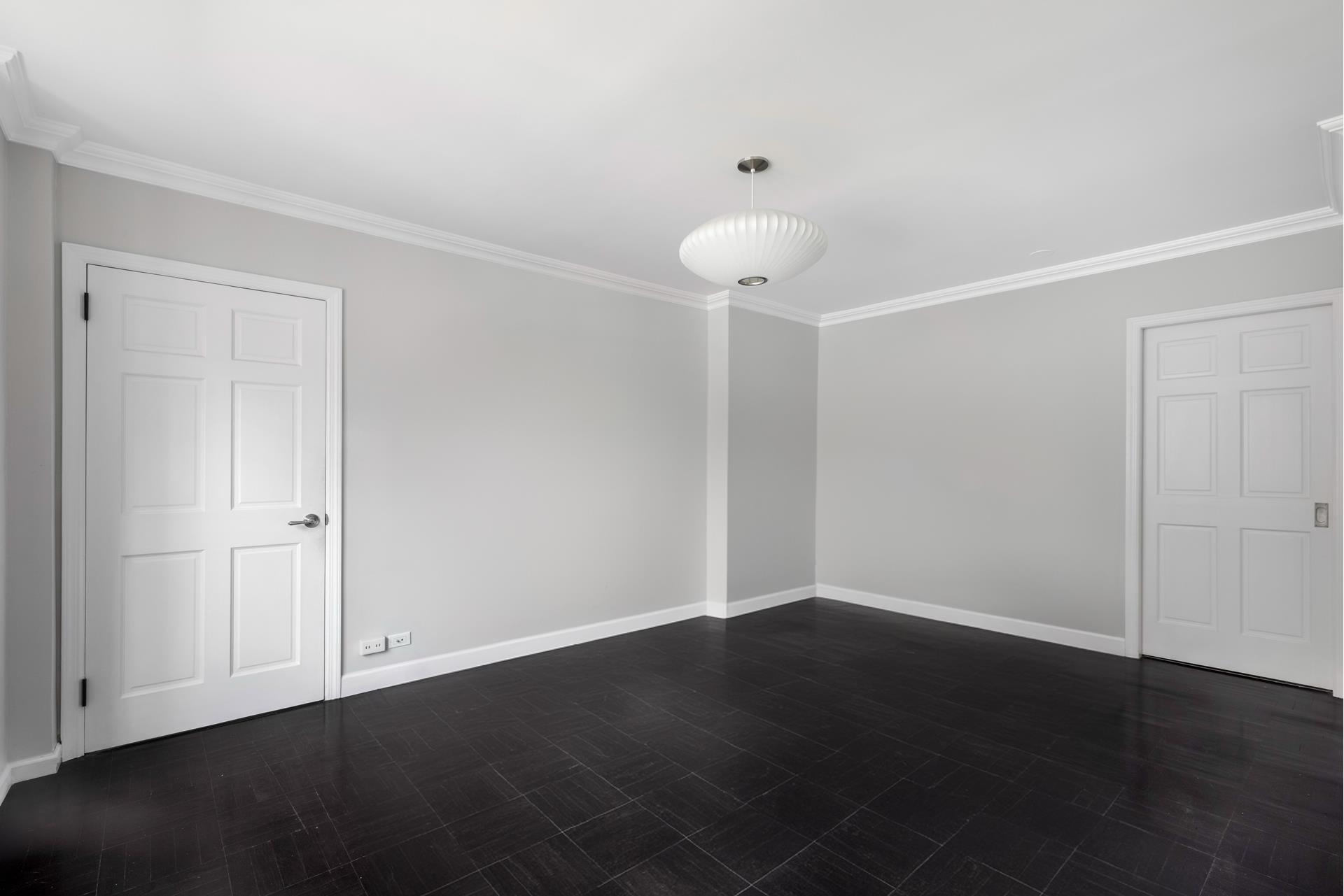 an empty room with wooden floor and fan