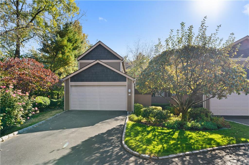 a view of a house with a small yard plants and large tree