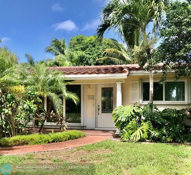 a view of a house with potted plants and a large tree