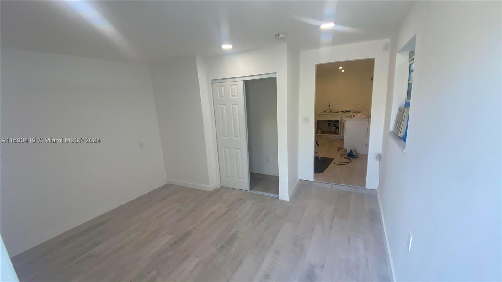 a view of a hallway with wooden floor and a bathroom