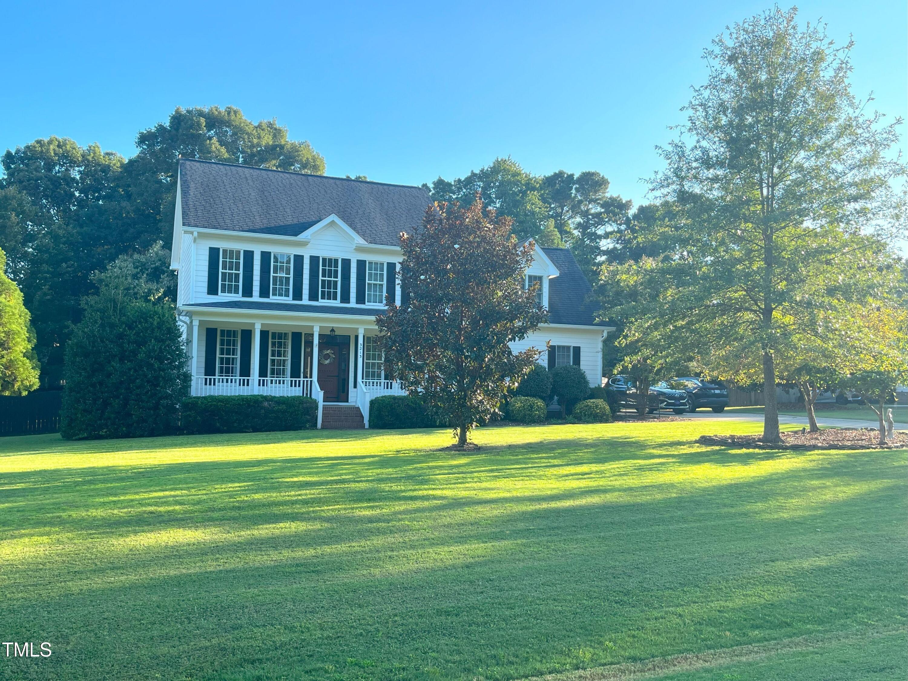 a view of a big house with a big yard and large trees