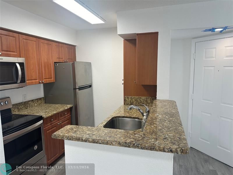 a kitchen with granite countertop a sink a stove and refrigerator