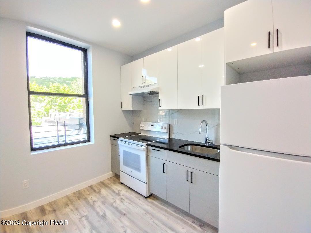 a kitchen with granite countertop white cabinets and white appliances