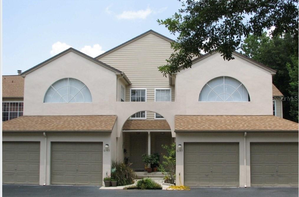 a view of a house with a garage and a large tree