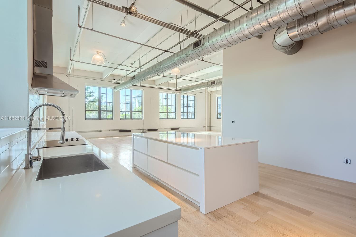 a large kitchen with a large window a sink and cabinets