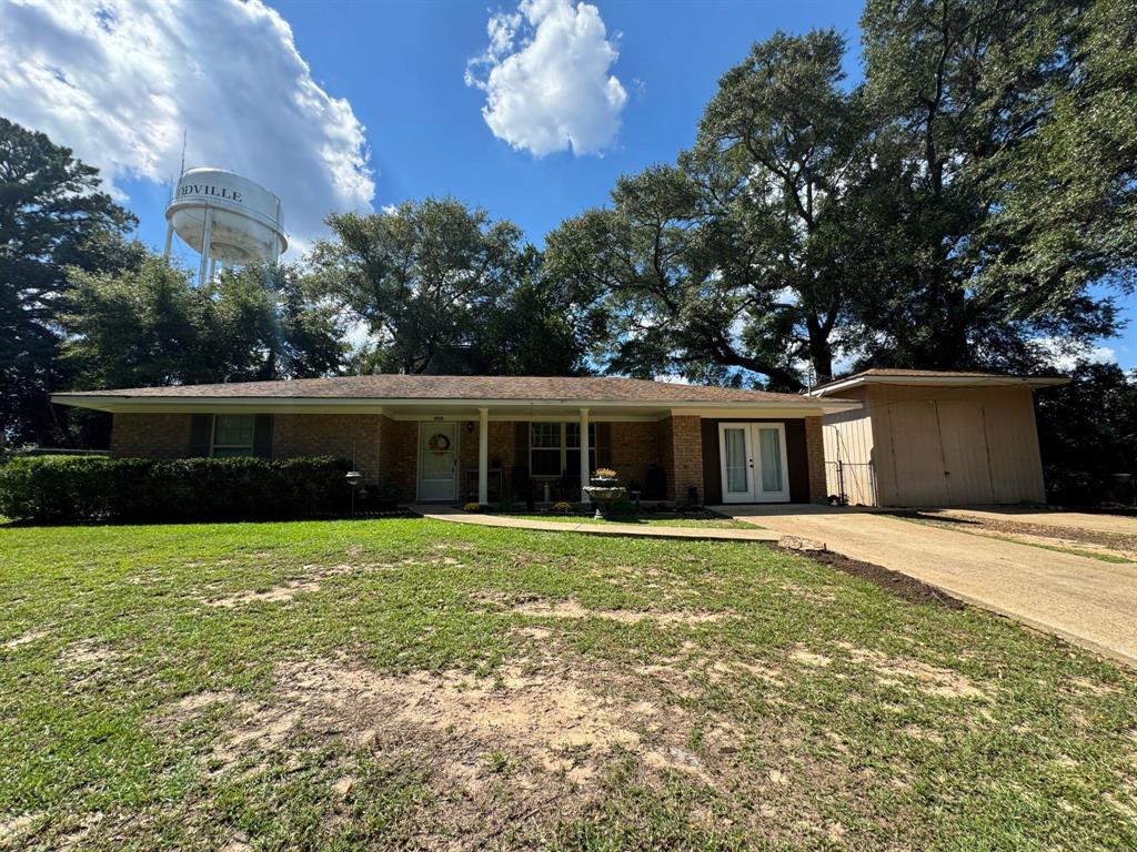 a front view of house with yard and trees in the background