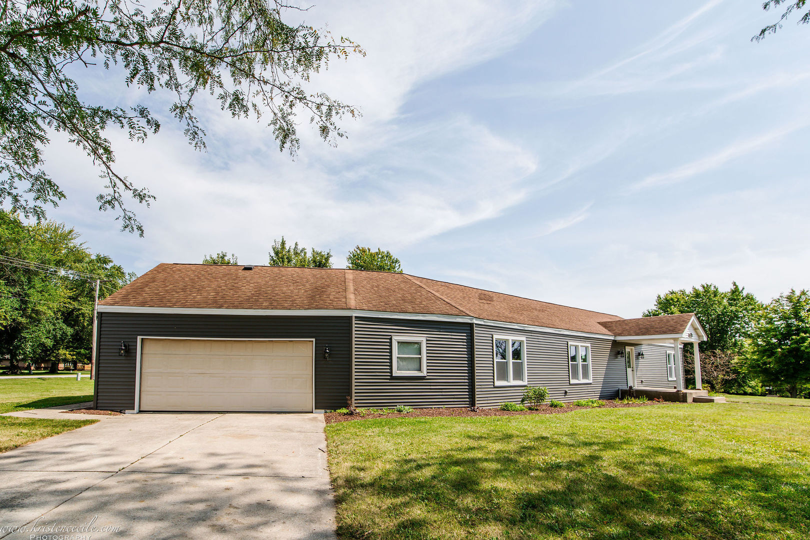 a front view of house with yard and trees in the background