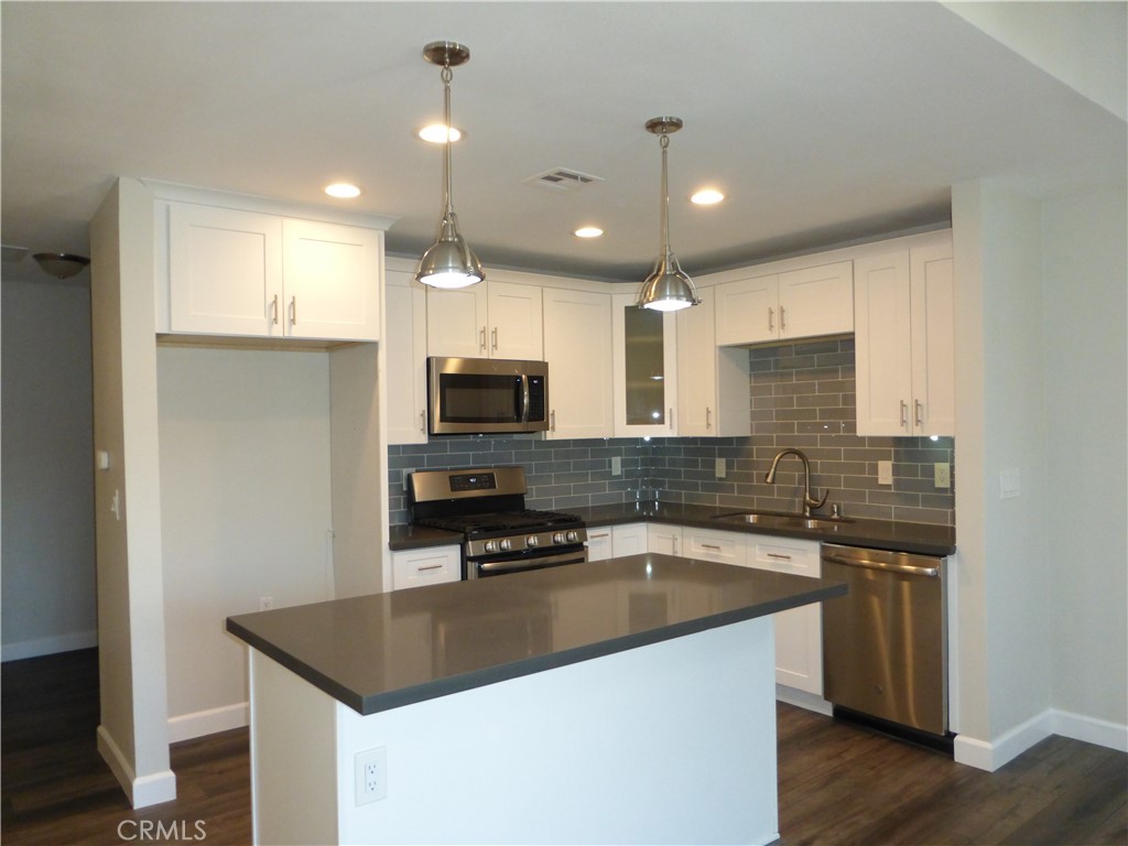 a kitchen with stainless steel appliances granite countertop a sink a stove and a refrigerator