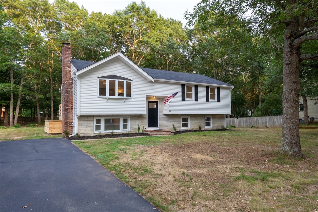 a view of a yard in front of a house with large trees