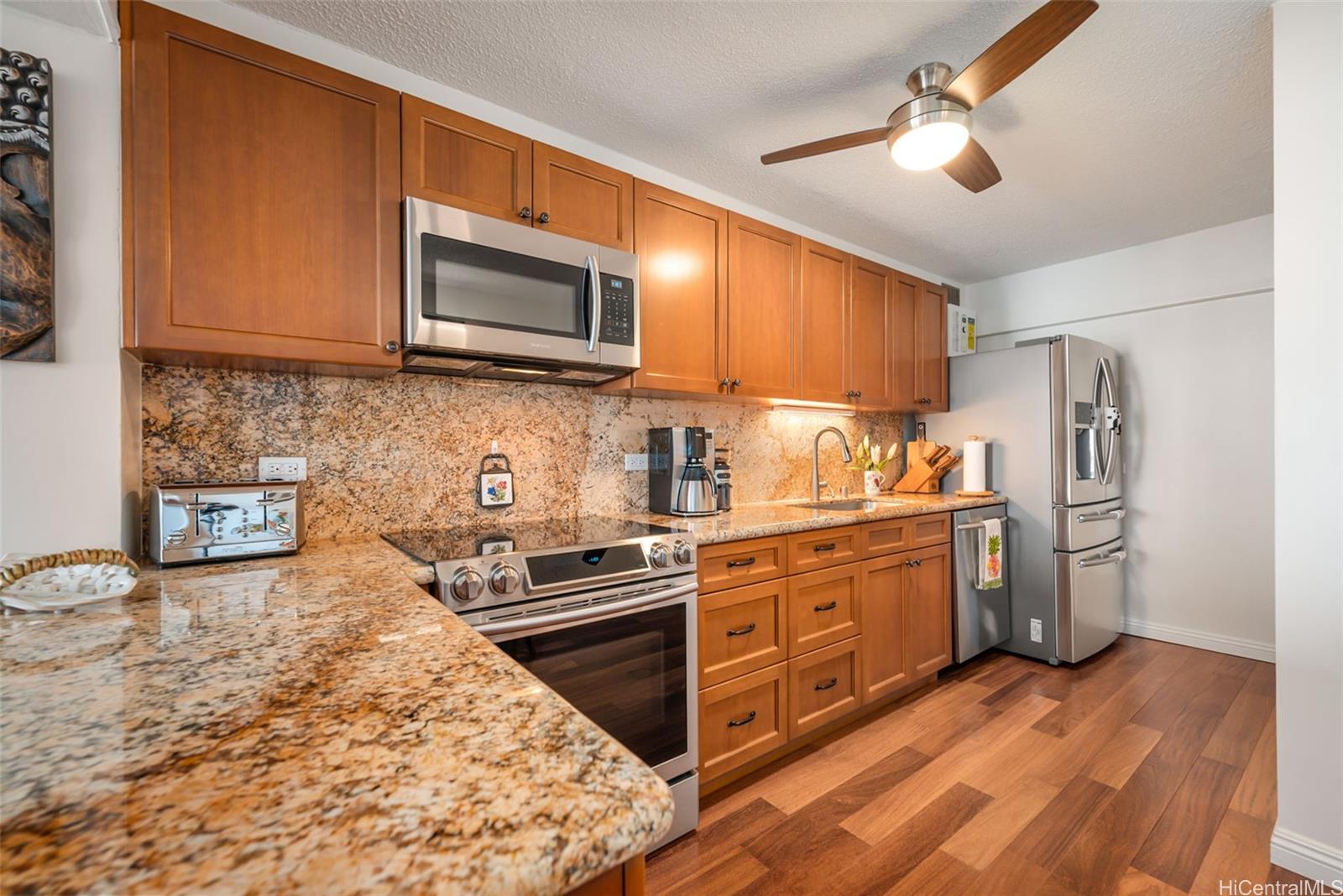a kitchen with stainless steel appliances granite countertop a stove top oven a sink dishwasher a refrigerator and cabinets with wooden floor