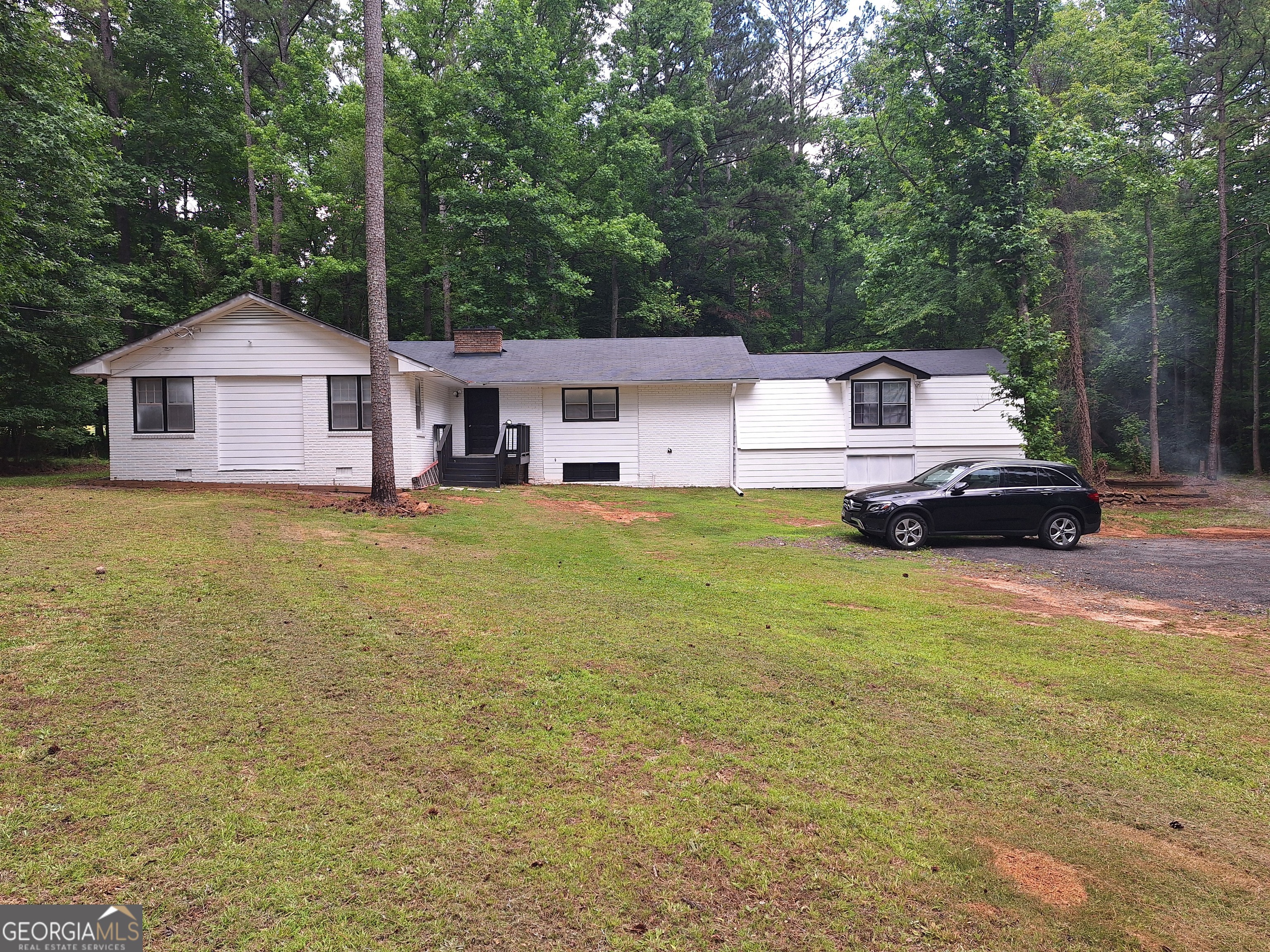 a front view of a house with a garden and trees