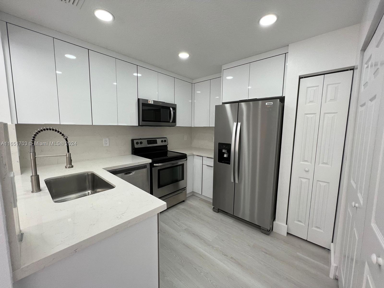 a kitchen with stainless steel appliances granite countertop a refrigerator sink and microwave