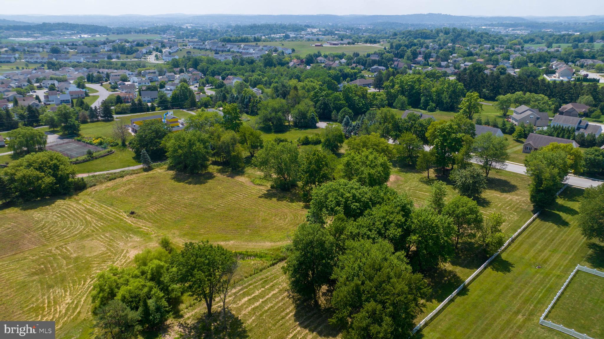 an aerial view of residential houses with outdoor space and trees