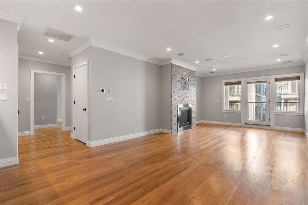 a view of an empty room with window and wooden floor