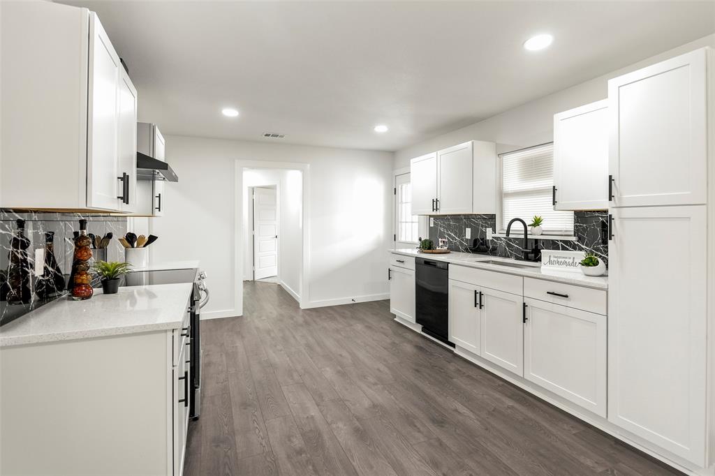 a kitchen with stainless steel appliances white cabinets sink and wooden floor