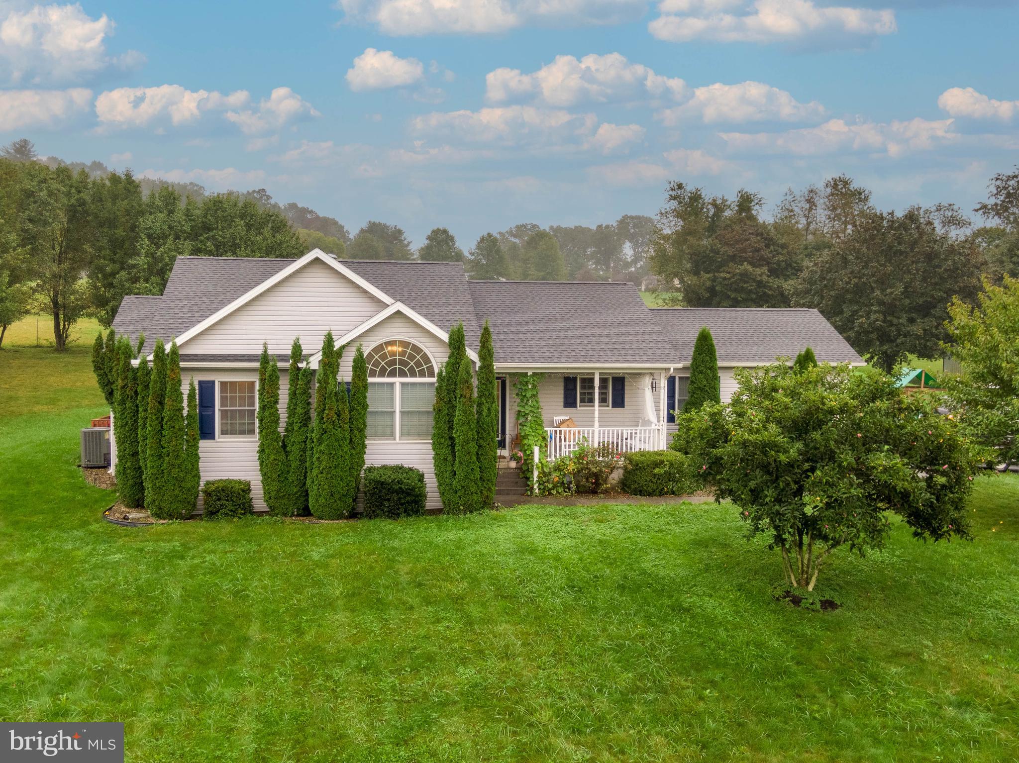 a view of a house with a big yard plants and large trees